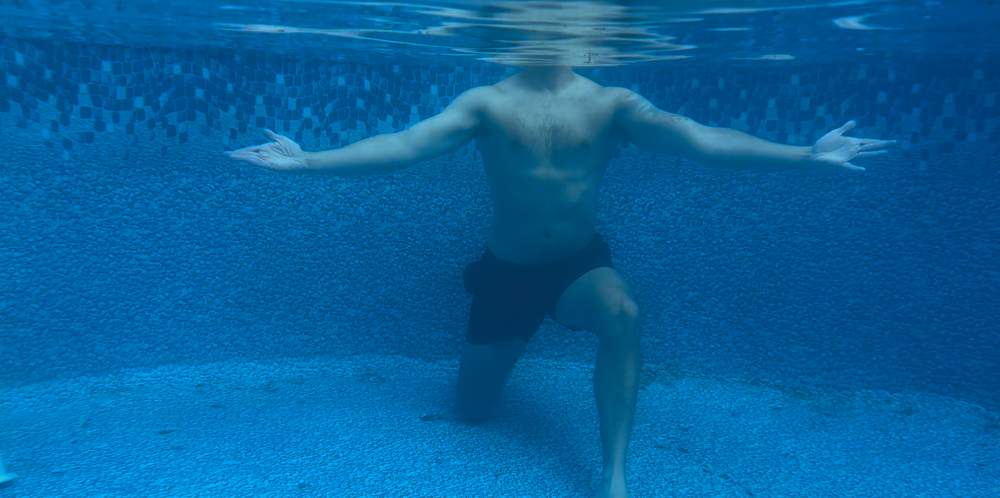 Man demonstrating Figure 8's with arms: aqua therapy exercise in a pool. Under water angle.