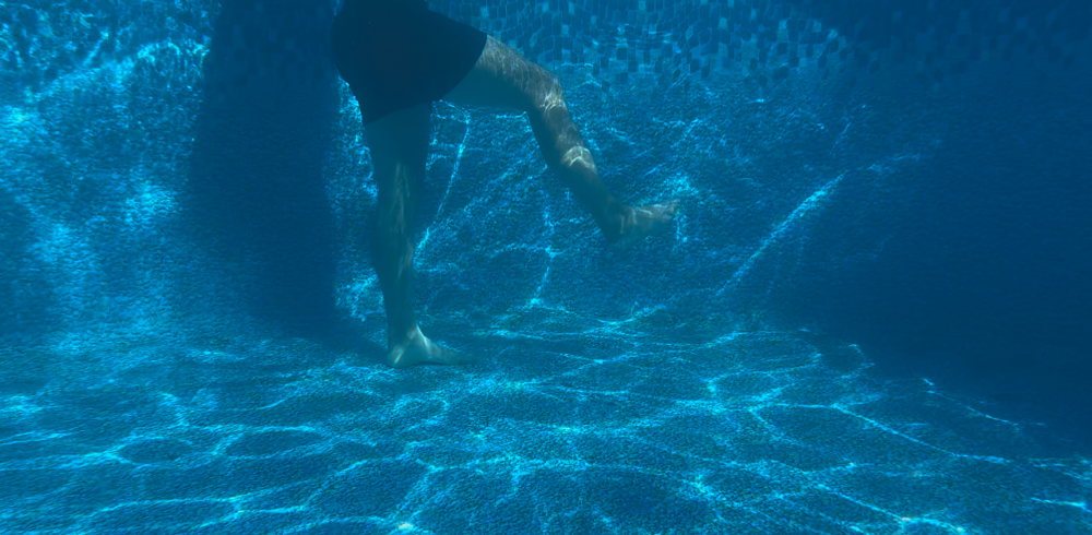Man demonstrating aqua therapy exercise, a bicycle. Under water angle.