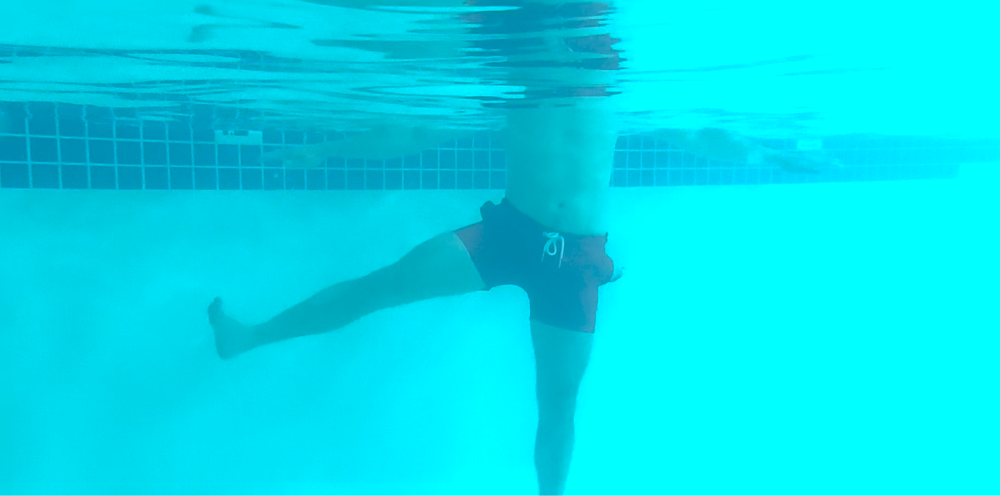 Man doing leg abduction and adduction aqua therapy pool exercise. Photo taken under water. 