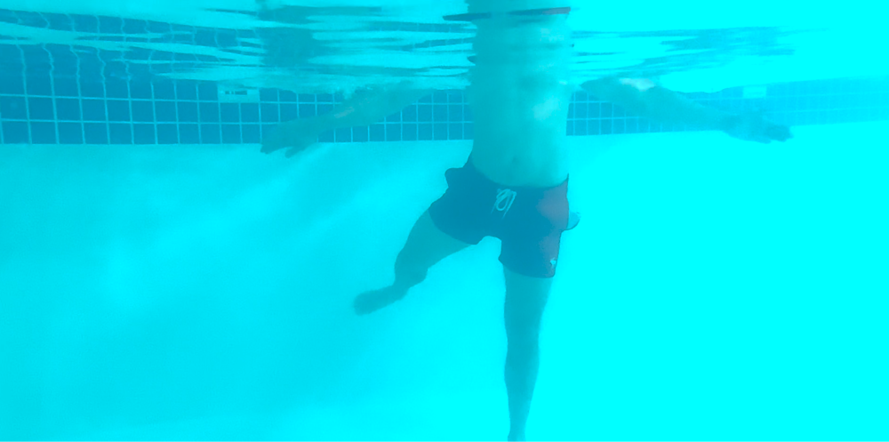 Man doing aqua therapy leg exercise, figure 8's in a pool. Underwater angle.