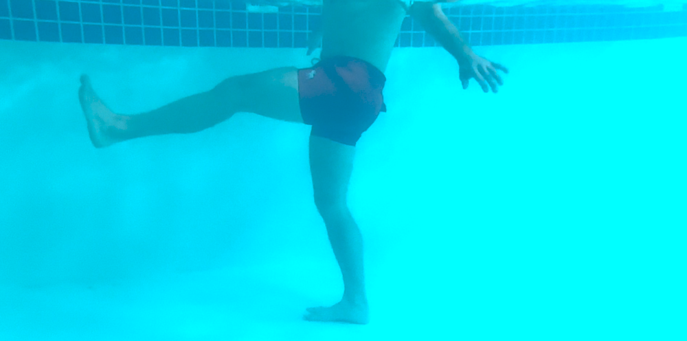Man doing leg flexion-extension aqua therapy exercise in pool. Photo taken under water.